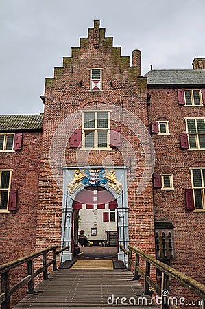 Medieval Ammersoyen Castle with its richly decorated entrance, brick walls and wooden bridge on cloudy day. Stock Photo