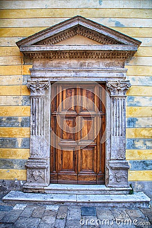 Medieval ancient wooden door with ornate stone columns, Italy. Stock Photo