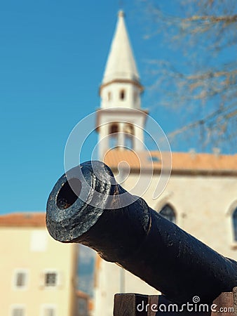 Medieval cannon in front of blurred Tower of St. John the Baptist Cathedral .in Budva in Montenegro Stock Photo