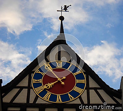 Medieval clock in tower of old building with blue sky background. The clock of hands marks 7:55 at the top of the tower there is a Stock Photo