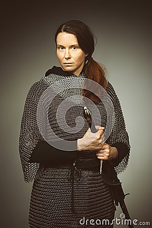 Armed woman in chain armor with sword posing for portrait in studio Stock Photo