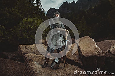 Medieval knight stands on rocks holding a sword Stock Photo