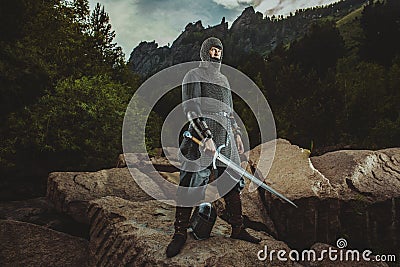 Medieval knight stands on rocks holding a sword Stock Photo