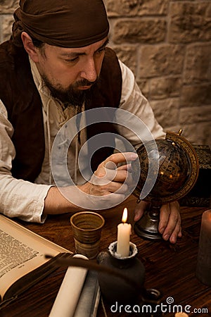Medieval man pointing at a old globe, concept travelling and tourism Stock Photo