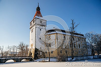 Medieval renaissance water castle with half-timbered tower with snow in winter sunny day, Historic Romantic chateau Blatna near Editorial Stock Photo