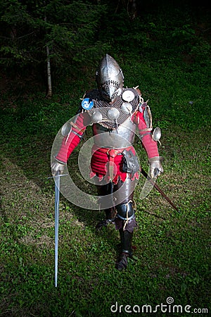 Medieval Warrior in Knight's Suit Standing in Dark Forest Ready for Battle, Full Length Shot Stock Photo