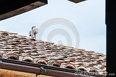 Medieval white catholic stone cross on top of the tiled roof Stock Photo