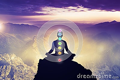 Meditating men in yoga lotus position with seven chakras. Mindfulness and self awereness practice. Silhiuette of meditation on mou Stock Photo