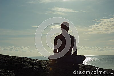 Meditating at Sunrise Overlooking Ocean Stock Photo