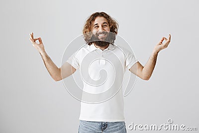 Meditation heals wounds in soul. Studio shot of calm and friendly easter bearded man spreading hands with zen gesture Stock Photo