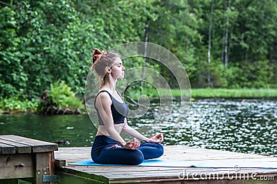 meditation by Young yogi girl on the pier of a beautiful lake. The concept of appeasement, healthy lifestyle Stock Photo