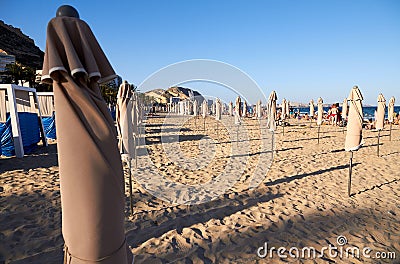 Mediterranean beach with some folded umbrellas Editorial Stock Photo