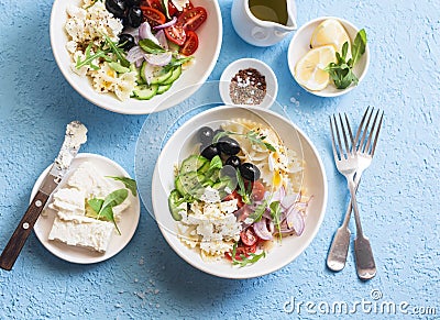 Mediterranean pasta salad. Pasta farfalle, tomatoes, cucumbers, olives, feta cheese and arugula salad. On a blue background, top Stock Photo