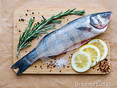 Raw uncooked sea fish preparation - seabass choice of fish on cutting board on the parchment paper. Mediterranean Stock Photo