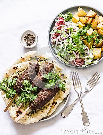 Mediterranean style lunch table. Meat kebab, garlic herb naan, yogurt dressing vegetable salad, roasted potatoes - delicious lunch Stock Photo