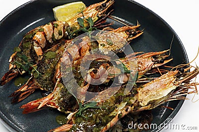 mediterranean style marinated grilled king tiger prawns or shrimps in a plate with white background Stock Photo