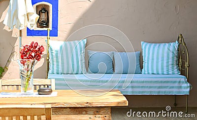 Mediterranean style terrace with wooden table, chair, flowers and sofa on a backdrop Stock Photo