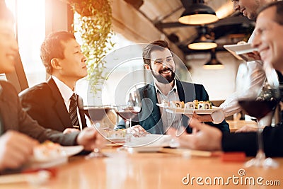 People sit at table eating sushi and drinking wine Stock Photo