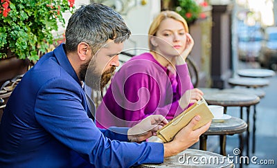 Meeting people with similar interests. Man and woman sit cafe terrace. Girl interested what he reading. Literature Stock Photo