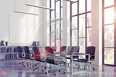 Meeting room interior with a long black table with laptops standing on it and a vertical poster on a white wall. Stock Photo