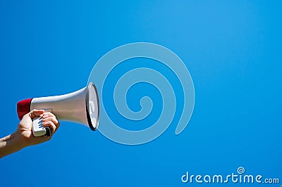 Megaphone in a female hand on a blue background. No people. Cropped photo. A woman holds a sound amplifier against the Stock Photo