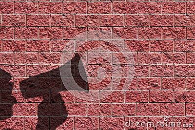 Megaphone speaking announcing man shadow against red brick wall background or wallpaper Stock Photo