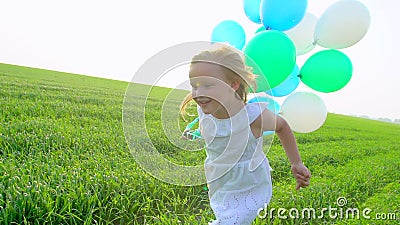 Meisje in een kleding die groen tarwegebied doornemen met in hand ballons Kind, jong geitje die in tuin lopen en stock footage Meisje in een kleding die groen tarwegebied doornemen met in hand ballons Kind, jong geitje die in tuin lopen en stock footage
