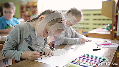 Meisjes met twee zussen tekenen met viltstiften op papier aan een tafel in een klaslokaal Voorschools leren op school stock video Meisjes met twee zussen tekenen met viltstiften op papier aan een tafel in een klaslokaal Voorschools leren op school stock video