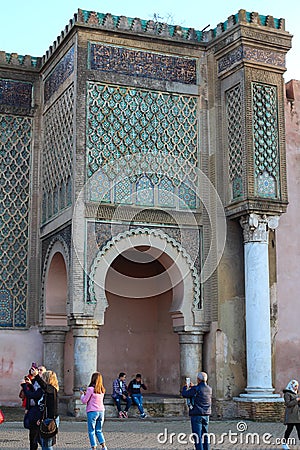 A fragment of the main and most beautiful gate of Meknes Bab-El-Mansur and tourists photographing them Editorial Stock Photo