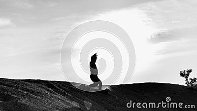 A black and white silhouette view of a young man running freely at the center of desert with sunset as background Editorial Stock Photo