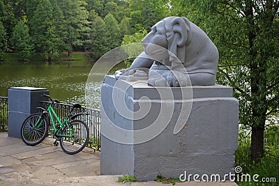 Melancholic stone lion guards a parked bike Editorial Stock Photo