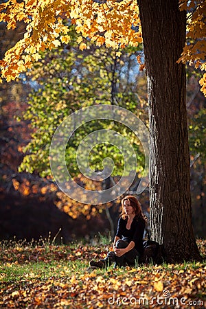 Melancholic woman rests under a tree Stock Photo