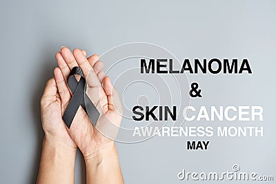 Melanoma and skin cancer, Vaccine injury awareness month and rest in peace concepts. Man holding black Ribbon on grey background Stock Photo