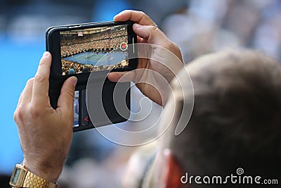 Unidentified spectator uses his cell phone to take images during tennis match at 2019 Australian Open in Melbourne Park Editorial Stock Photo