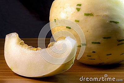 Melon of the snow leopard or matisse or dino variety on a wooden table Stock Photo