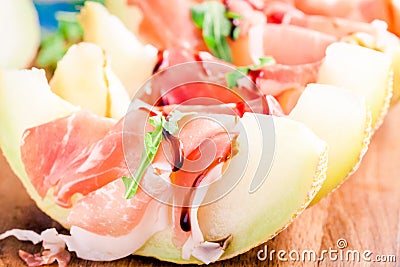 Melon with thin slices of prosciutto and arugula leaves Stock Photo