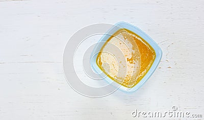Melted butter in light blue dish on white wooden table Stock Photo