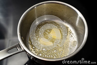 Melting butter in a stainless steel saucepan on the black stove, cooking concept, selected focus Stock Photo
