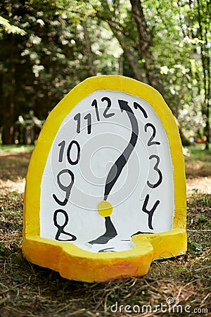 Melting clock art object lying on forest ground outdoor art exhibition, atmospheric surreal concept Editorial Stock Photo