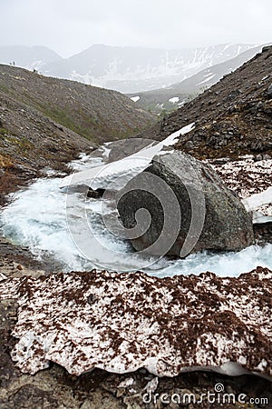 Melting water flowing from mountains from pass between glaciers and snow. The Khibiny, Kola peninsula, Russia Stock Photo