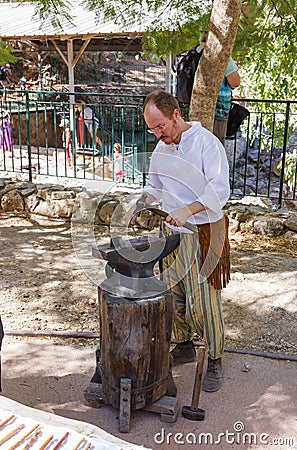 Member of the annual festival of Knights of Jerusalem, dressed as a blacksmith forges iron detail Editorial Stock Photo