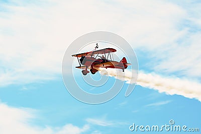 Memorial Airshow. Red Stearman biplane flying towards camera while trailing smoke in exhibition Editorial Stock Photo