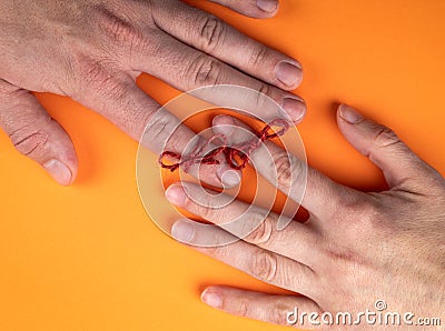 Memory and Reminder Knot. Female and male hands on an orange background Stock Photo