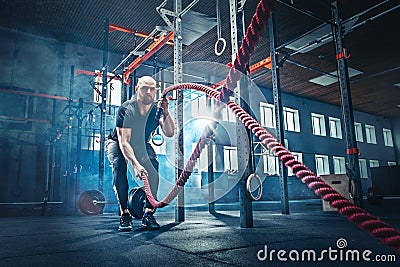 Men with battle rope battle ropes exercise in the fitness gym. Stock Photo