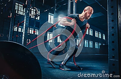 Men with battle rope battle ropes exercise in the fitness gym. CrossFit. Stock Photo