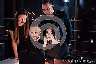 Only man with beard is serious. Team of young business people works on their project at night time in the office Stock Photo