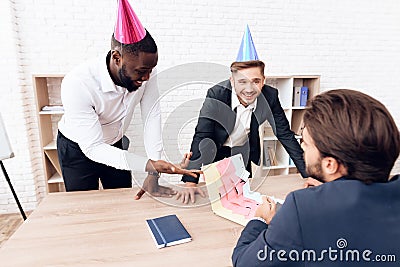 Men in business suits and festive hats stuck a notebook of their colleague with stickers. Stock Photo