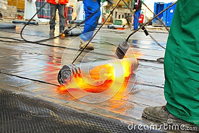 Men crout roof with hot tar Stock Photo