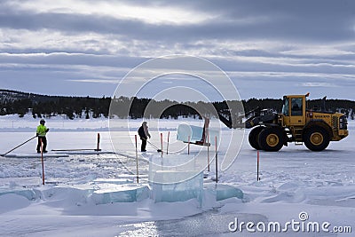 Men cut ice blocks from a frozen lake needed to build the Ice hotel in Juakkasjärvi, Sweden Editorial Stock Photo