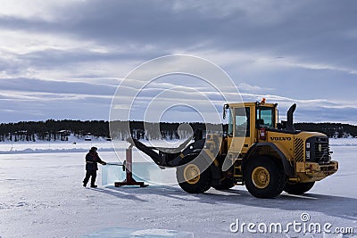 Men cut ice blocks from a frozen lake needed to build the Ice hotel in Juakkasjärvi, Sweden Editorial Stock Photo